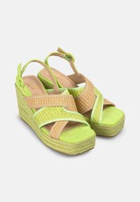 Sandali con zeppa, con cinturini verde e beige, caratterizzati da un design intrecciato testurizzato. Parte superiore in morbido tessuto verde su una suola in corda naturale.
