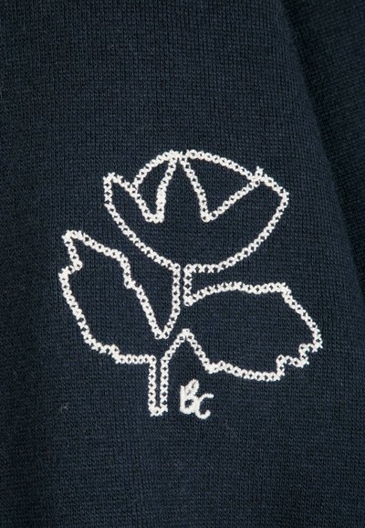 Contour brodé blanc d’une fleur avec trois pétales et deux feuilles sur un tissu tricoté bleu foncé avec les petites initiales "bc" en dessous.