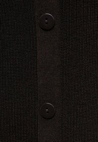 Cardigan en tricot noir avec une texture côtelée, des boutons noirs mats et un détail de couture verticale claire.