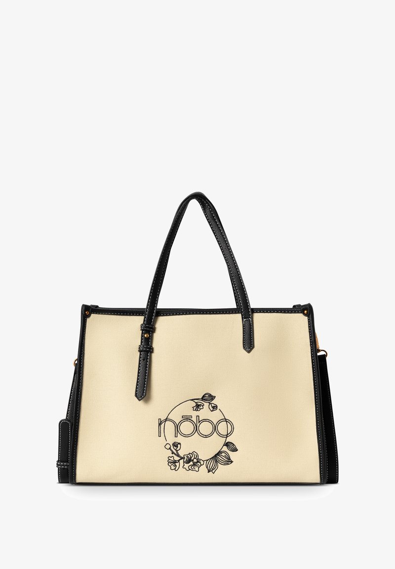 Beige canvas tote bag met zwarte synthetische leren accenten, handvatten aan de bovenkant en geborduurde bloemenlogo aan de voorkant. Heeft een gestructureerd ontwerp.