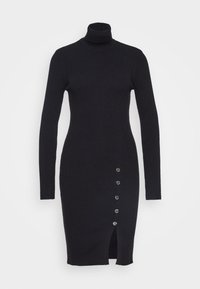 Černé žebrované pletené šaty s vysokým límcem, dlouhými rukávy, bočním rozparkem a pěti dekorativními knoflíky na levé straně.