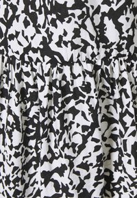 Tissu à motifs noir et blanc avec un design abstrait, présentant des plis à la taille, fabriqué en matériau léger.