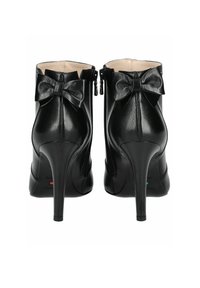 Bottines en cuir noir avec un talon aiguille haut, ornées d'un nœud décoratif à l'arrière et de fermetures éclair sur les côtés.