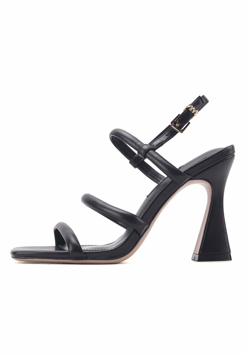 Black high-heeled sandal with slender straps, open toe, adjustable buckle, and a geometric heel design. Smooth leather texture.