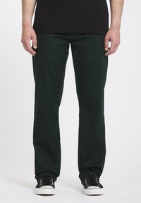 Donkergroene katoenen broek met een rechte snit, voorzien van zakken, gecombineerd met zwarte sneakers en een plain zwart T-shirt.