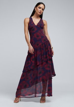 Maxi sukienka z głębokim dekoltem w kształcie litery V, warstwowymi falbanami oraz kwiatowym wzorem w czerwieni na ciemnofioletowym tle. Wykonana z lekkiego, przezroczystego materiału.