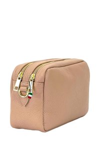 Roze leren cosmetica tas met gouden ritsen, rechthoekige vorm, gestructureerde afwerking en een klein Italiaans vlaggetje accent nabij de rits.