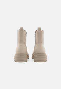 Beige ankler støvler med en glat ruskindsfinish, sidelukninger og en chunky, rillede sål. Har minimal syning og en pull-tab.