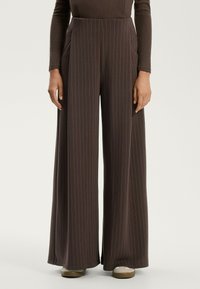 Wijde broek van bruin stof met verticale witte strepen, hoge taille en zijzakken. Gladde textuur, comfortabele pasvorm.