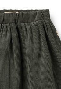 Jupe en velours côtelé vert foncé avec taille élastique, présentant une texture en côtes verticales et des plis froncés pour plus de volume.