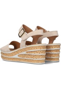 Beige suede wiggen sandalen met een kurken platform. Voorzien van een verstelbare band met een gouden gesp en een uitgesneden ontwerp. Gekartelde witte zool.