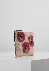 Beaded beige clutch with three purple, red, orange, and black floral patterns standing on a white pedestal against a plain gray backdrop.