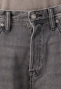 Sive jeans iz denima z gumbom in zadrgo, z obročem za pas, subtilno teksturo in kontrastnimi šivi.