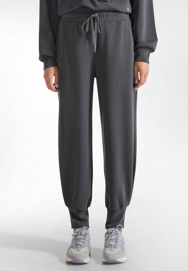 Graue Jogginghosen aus weichem Stoff, mit einem elastischen Taillenbund und Kordelzug, schmal zulaufenden Bündchen und einer glatten Textur.