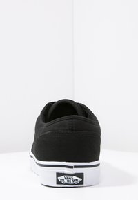 Sneaker nera in tela con cuciture bianche, collo imbottito e suola in gomma. Presenta un'etichetta logo in bianco e nero sul retro.