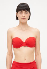 Rdeč bandeau bikini zgornji del z nabranim materialom na sredini in gladko, raztegljivo teksturo. Oblikovanje vključuje brezšivno izdelavo in brez naramnic.