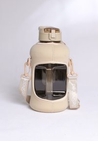 Bouteille d'eau isolée beige avec un centre transparent, un couvercle en plastique et une finition texturée. Comprend une sangle amovible étiquetée "BeShaped".
