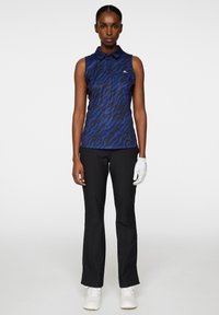 Sleeveless blue polo with a tiger stripe pattern, paired with black trousers and a white glove. Smooth fabric and tailored fit.