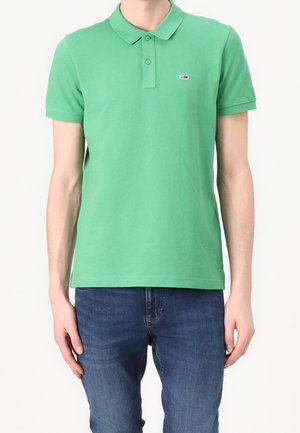Groen katoenen poloshirt met een kraag, korte mouwen en een klein logo op de borst. Gecombineerd met een blauwe spijkerbroek.