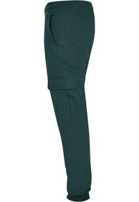 Pantaloni jogger din bumbac verde, cu croi conic, cu manșete ribbate, buzunare laterale și un buzunar tip cargo pe coapsa stângă. Textură netedă.