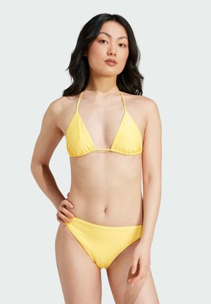 Bikini giallo con top triangolare e slip abbinati. Tessuto liscio, design minimale e spalline sottili. Dettagli logo discreti sul top.