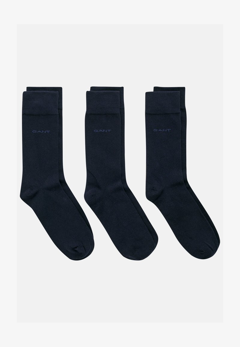Ensemble de chaussettes en coton bleu marine, présentant une texture lisse et des bords côtelés. Chaque chaussette affiche le logo "GANT" en bleu clair contrastant.