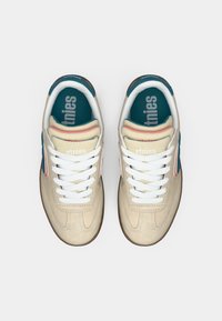 Μπεζ σουέτ αθλητικά παπούτσια με λευκές ταινίες, μπλε και ροζ λεπτομέρειες, και μαλακή σόλα που φέρει το λογότυπο "etnies". Ορατή καουτσούκ σόλα.