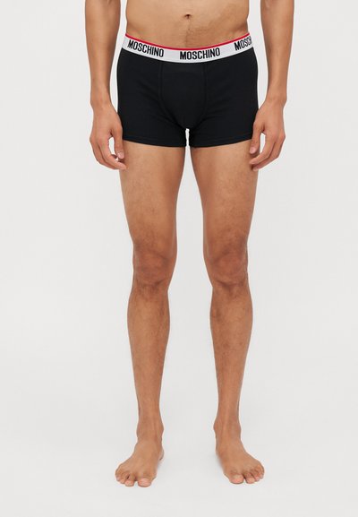 Sorte bomulls boxershorts med hvit midjebånd med røde detaljer og logoen "MOSCHINO" gjentatt langs toppen. Glatt tekstur.