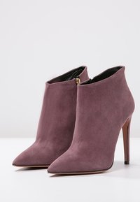 Zamszowe botki za kostkę w kolorze mauve, z wąskim noskiem i szpilkowym obcasem, z bocznym zamkiem błyskawicznym i gładką podszewką.