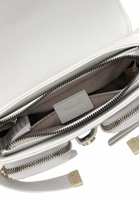 Borsa a mano in pelle bianca con chiusura a zip, tasche interne e dettagli in metallo dorato. Texture liscia con caratteristiche di design minimalista.