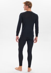 Black long-sleeve top and leggings made from a smooth, stretchable material. Fitted design with ribbed cuffs and seams. Barefoot model.