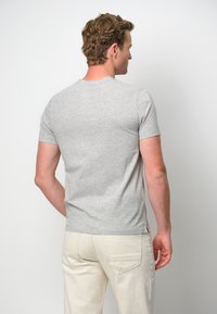 Grå kortärmad t-shirt i en mjuk bomullsblandning, med en klassisk halsdesign, något figurnära passform och en etikett på vänster sidsöm.