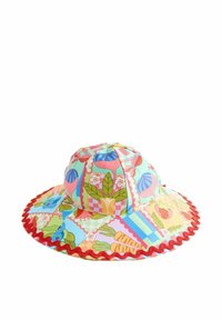 Chapeau de soleil à large bord en tissu coloré à motifs de feuilles, fleurs et fruits, avec une bordure rouge festonnée le long du bord.