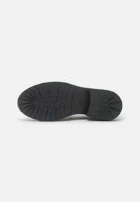 Sole in gomma nera con profondi profili e scanalature definite per una migliore aderenza. Nessun ulteriore accento o motivo visibile. Forma del tacco arrotondata.