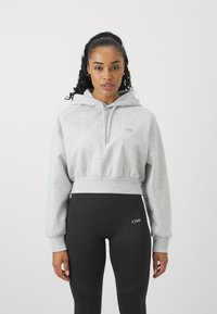 Felpa grigia corta con cappuccio regolabile, vita a coste e logo ricamato, abbinata a leggings neri a vita alta con dettagli a contrasto.