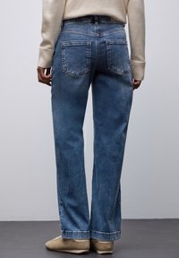 Jeans in denim azzurro chiaro con taglio dritto, cinque tasche e sfumature leggere. I bordi sono rifiniti in modo pulito, senza decorazioni.