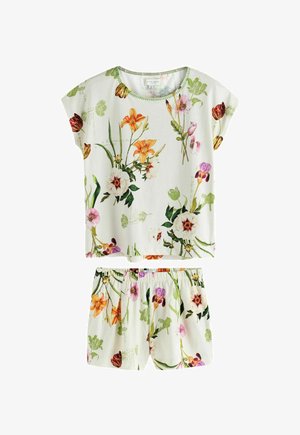 Close-up van een hand die bloemige stof vasthoudt met tulp- en bladpatronen op een witte geplooide elastische tailleband.