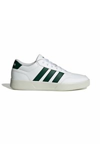 Zapatilla blanca con detalles verdes, que presenta tres rayas, parte superior de cuero texturizado, puntera redonda y suela de goma. Los cordones son blancos.
