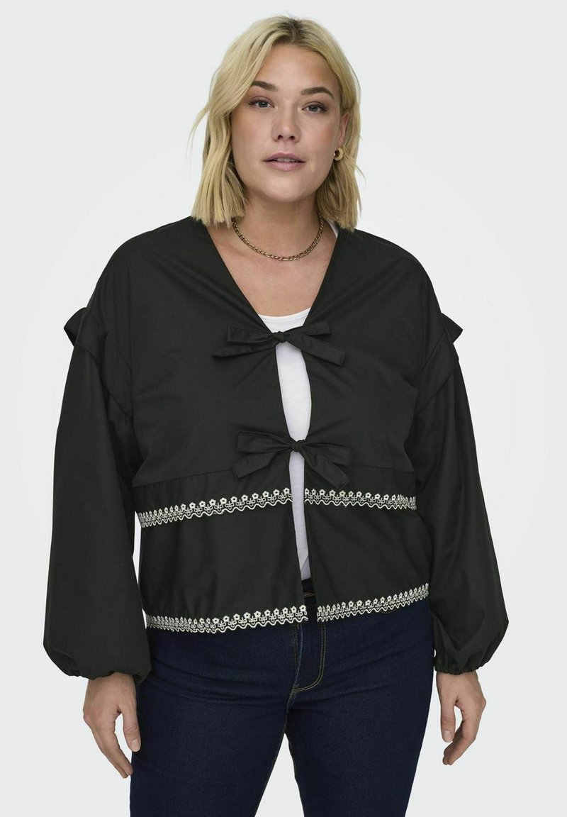 Czarna krótka kurtka z długimi rękawami, z dwoma kokardami z przodu i białą koronką na brzegu. Miękki materiał o luźnym kroju.