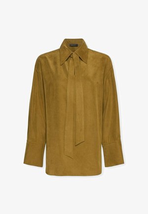 Blouse en suède marron moutarde à manches longues avec col large et détail de nœud à l'avant, poignets boutonnés et texture lisse.