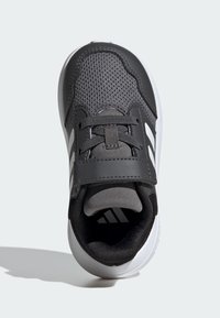 Černá atletická obuv s prodyšným síťovaným svrškem, šedými akcenty, elastickými tkaničkami a bílou gumovou podešví. Má design slip-on.