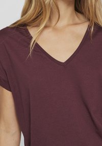 Bordeauxfarbiges V-Neck-T-Shirt aus weichem Stoff; kurze Ärmel; dezente Textur; einfaches Design.