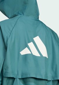 Teal hooded jacket made of lightweight fabric, featuring a large white three-stripe logo on the back, with seamless design elements.