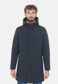 Parka blu navy con zip frontale, due tasche laterali e cappuccio. Realizzata in tessuto liscio e imbottito con una finitura leggermente testurizzata.