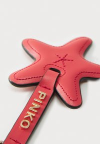 Pink leather starfish keychain with embossed detailing and a gold "PINKO" brand logo. Features a smooth texture and sleek black edges.