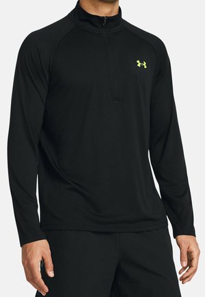 Maglietta sportiva nera a maniche lunghe con collo a mezza zip. Presenta una texture liscia, una vestibilità slim e un piccolo logo neon sul petto.