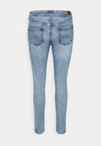 Pantalones vaqueros ajustados de color azul claro, fabricados en denim, que presentan un diseño clásico de cinco bolsillos y detalles de costura en los bolsillos traseros.