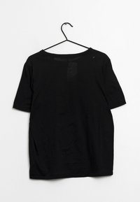 Camiseta negra de manga corta con un corte relajado y una etiqueta visible en la parte de atrás. La tela parece suave, con una textura lisa y sin patrones.