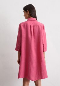 Rozā lina krekla kleita ar pogām pie aprocēm, apkakli un brīvu A formas siluetu. Tekstūru audums ar viegli izstieptu izskatu.