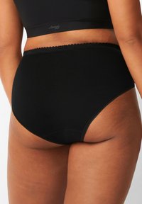 Slip nero a vita alta realizzato in tessuto morbido, con una vita scallop e una texture liscia per il massimo comfort. Nessun logo o motivo visibile.